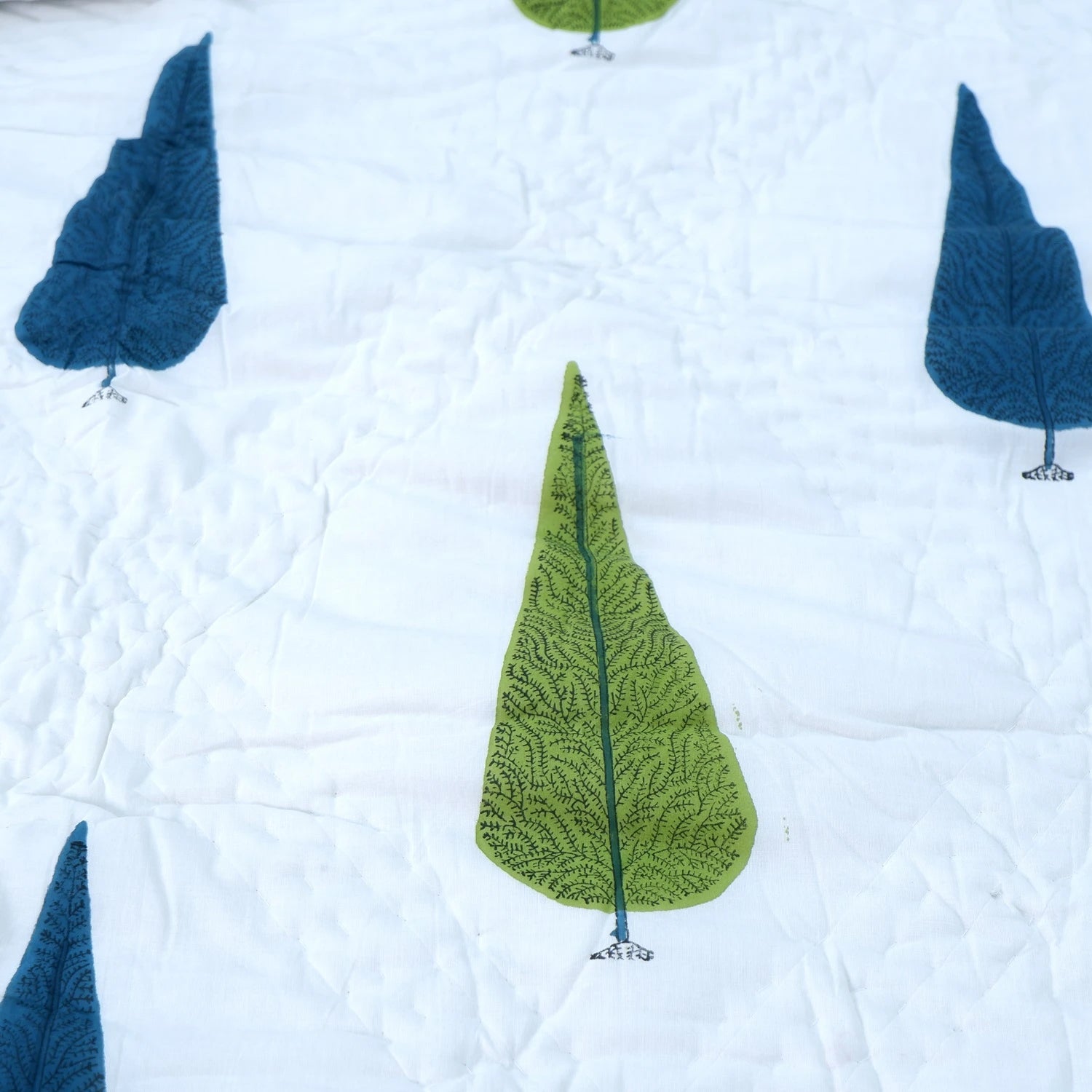 Jaipuri block print quilt set featuring vibrant leaf designs in blue and green on a white background